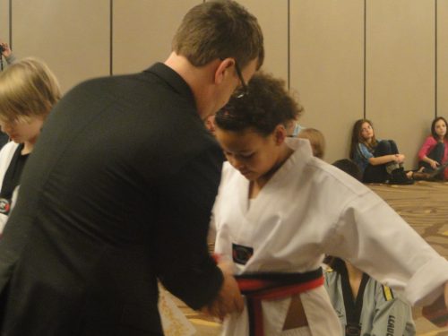 The owner of the studio tying on her new black belt after 3 hours of testing.